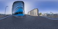 a curved building sits on the side of the road with buildings behind it in the background