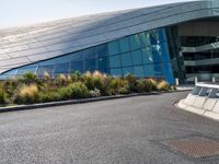 there are trees and plants around a curved building that resembles a futuristic structure, with large windows on top