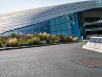 there are trees and plants around a curved building that resembles a futuristic structure, with large windows on top