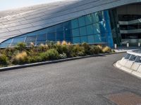 there are trees and plants around a curved building that resembles a futuristic structure, with large windows on top