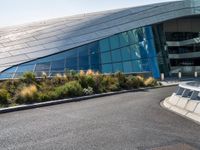 there are trees and plants around a curved building that resembles a futuristic structure, with large windows on top