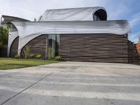 the home's exterior is a modern, curving, patterned structure with an open roof