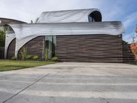 the home's exterior is a modern, curving, patterned structure with an open roof