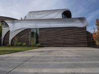 the home's exterior is a modern, curving, patterned structure with an open roof