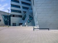 the large building has a large blue facade and a long grey bench in the front