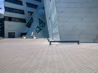 the large building has a large blue facade and a long grey bench in the front