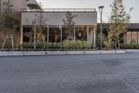 the outside view of a modern, empty store front in the evening hours, with trees and plants lined a street