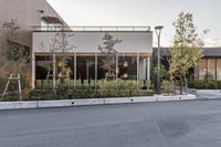 the outside view of a modern, empty store front in the evening hours, with trees and plants lined a street