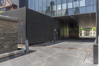 a very long entrance to a large glass building, with a parking meter near the entrance