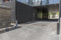 a very long entrance to a large glass building, with a parking meter near the entrance