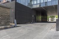 a very long entrance to a large glass building, with a parking meter near the entrance