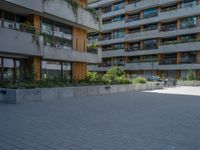 a skateboarding rider on the sidewalk outside an apartment building and some people in a blue shirt