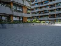 a skateboarding rider on the sidewalk outside an apartment building and some people in a blue shirt