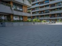 a skateboarding rider on the sidewalk outside an apartment building and some people in a blue shirt