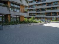 a skateboarding rider on the sidewalk outside an apartment building and some people in a blue shirt