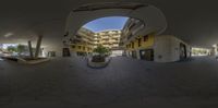 fisheye panoramic view of a parking garage with parking and large buildings near it