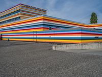 an empty parking lot painted brightly stripes on the wall of the building and sky as well as stones