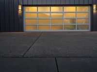 a modern garage door on a concrete sidewalk in front of a gray metal building at dusk