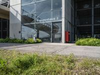 a building has a staircase going up the outside wall to it from which two fire hydrants sit on a grass and flowery area