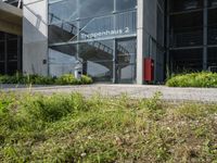 a building has a staircase going up the outside wall to it from which two fire hydrants sit on a grass and flowery area