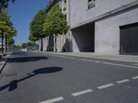 an empty street with some trees on the side of it and a building in the background