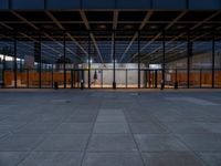 people in an empty glass building with lights on a platform next to them are standing