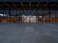 people in an empty glass building with lights on a platform next to them are standing