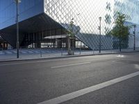 a building made from glass with an entry way below it and a street light beside it