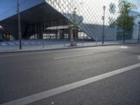 a building made from glass with an entry way below it and a street light beside it