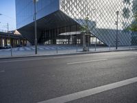 a building made from glass with an entry way below it and a street light beside it