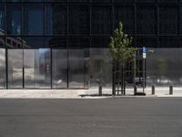 a city street has a bench on it near a modern glass building and street signs