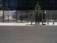 a city street has a bench on it near a modern glass building and street signs