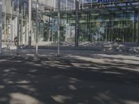 a large glass building with a person walking in front of it on a street in the middle of the day