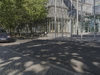 a large glass building with a person walking in front of it on a street in the middle of the day