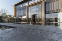 large glass window building next to water pool with reflection in window above concrete flooring