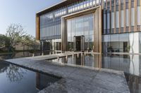 large glass window building next to water pool with reflection in window above concrete flooring