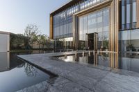 large glass window building next to water pool with reflection in window above concrete flooring