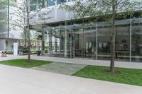 a building that has many glass windows and is in the grass area with benches outside