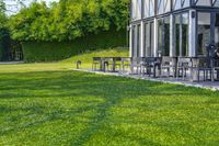 large patio in front of glass covered building with lawn area between it and trees outside