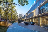 a courtyard next to a modern, glass building with blue lighting and large glass windows