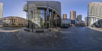 a very large glass building next to a city street on a sunny day taken in a fish eye lens