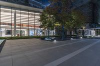 a large glass building with plants next to it and some trees in front of it