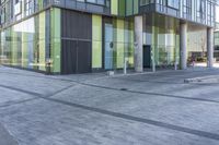 a large glassy office building with concrete and green panelsed walls in front of it