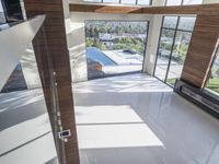 a room with a sliding glass wall and floor, with a large pool in the middle