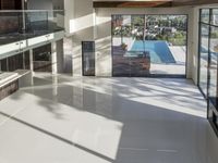 a room with a sliding glass wall and floor, with a large pool in the middle