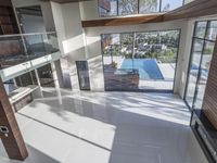 a room with a sliding glass wall and floor, with a large pool in the middle