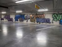 a parking garage with lots of graffiti written on the wall and floors of it,