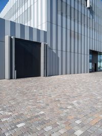 a grey building with some doors outside it and windows on each side of the building