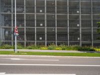 a building near the street has many plants and grass on it's side in front of the street