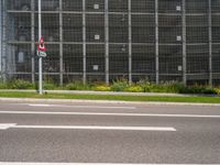 a building near the street has many plants and grass on it's side in front of the street